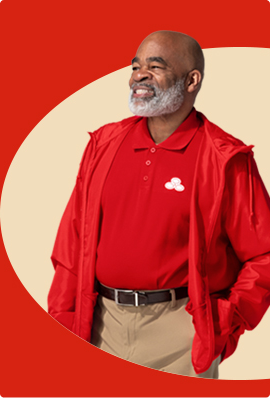 A bearded State Farm agent in red polo shirt and pullover smiles.